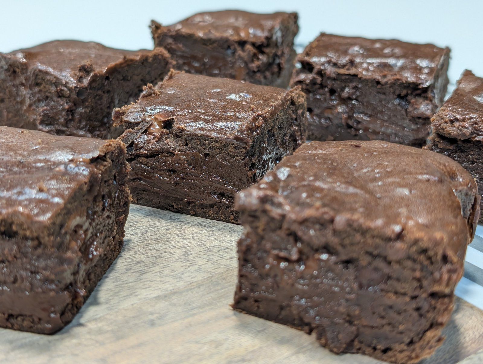 Cuadrados de brownie de chocolate oscuros, densos y húmedos, cortados en cubos sobre una tabla de madera.